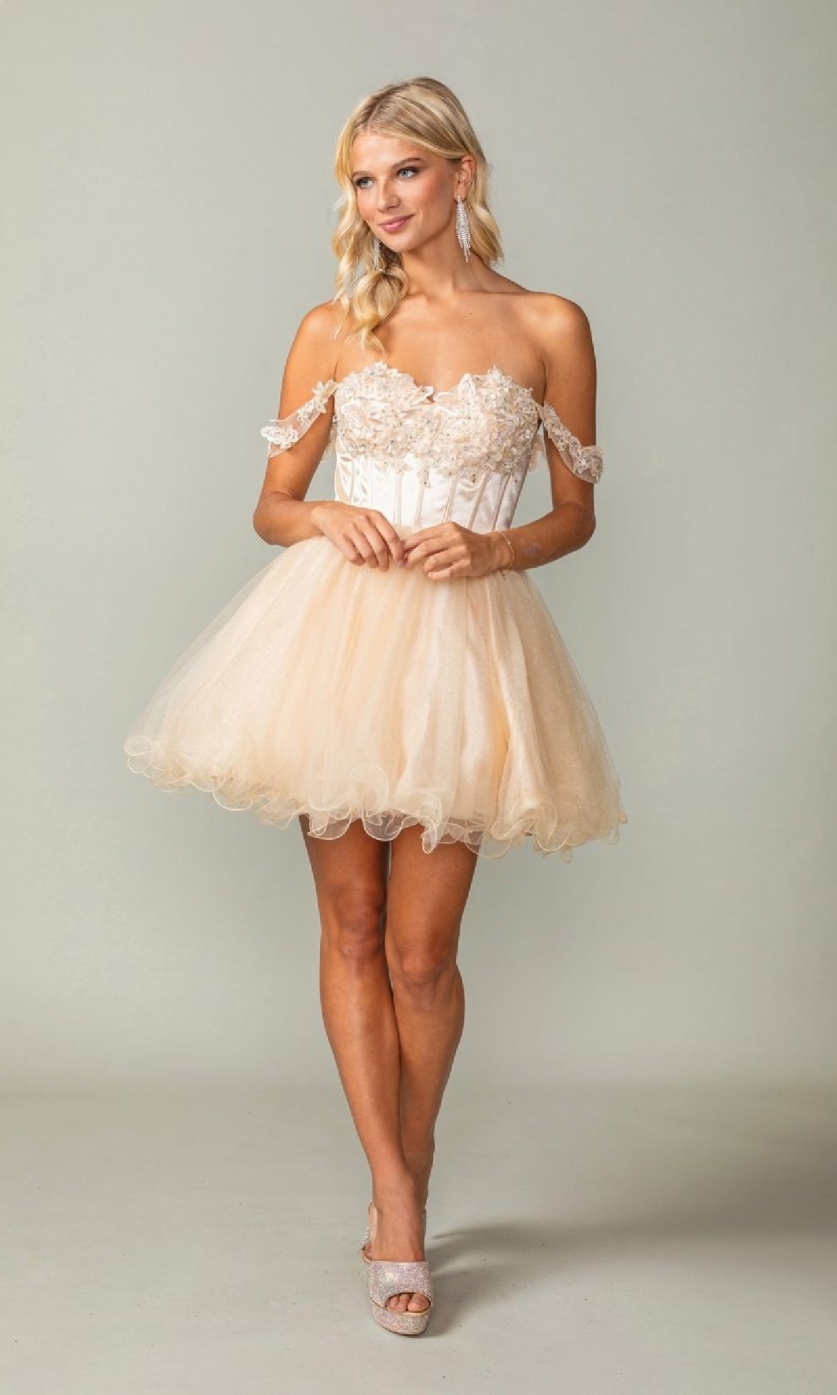 Woman wearing a short champagne colored dress against a plain background